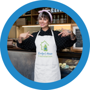 Girl Wearing Evelyn's House Foundation Apron - Symbol of Community and Service